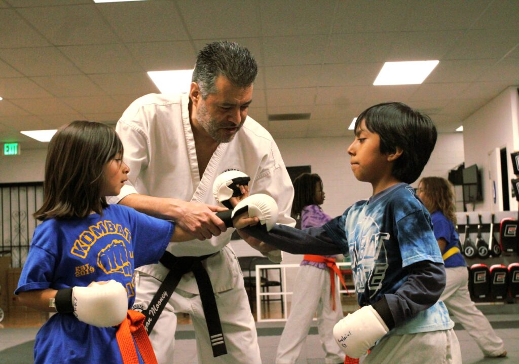 Sensei Ryan working one-on-one with children during karate training at Kombat Karate in Long Beach, CA